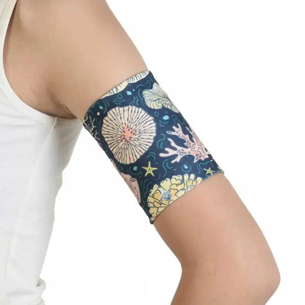 Glucose sensor armband in sea and beach design on upper arm.