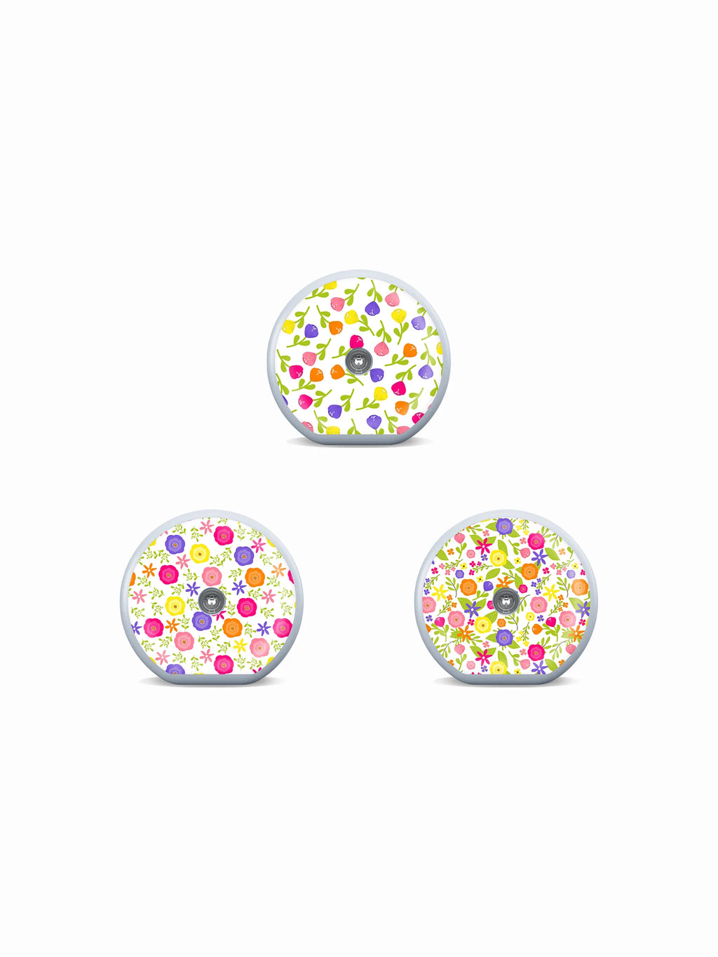 Three Accu-Chek SmartGuide sensor stickers with colorful buds, flowers and garden-inspired patterns on white.