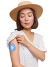FreeStyle Libre 2 drop shape patch worn on a woman’s arm, with breathable adhesive fabric for sensor support