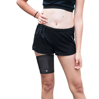 Leg band for insulin pump worn on woman's thigh under shorts, providing convenience and style.